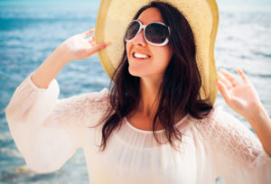 Woman with hat, sunglasses, and shirt trying to minimize sun exposure