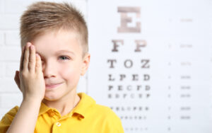 Child holding one eye for eye exam
